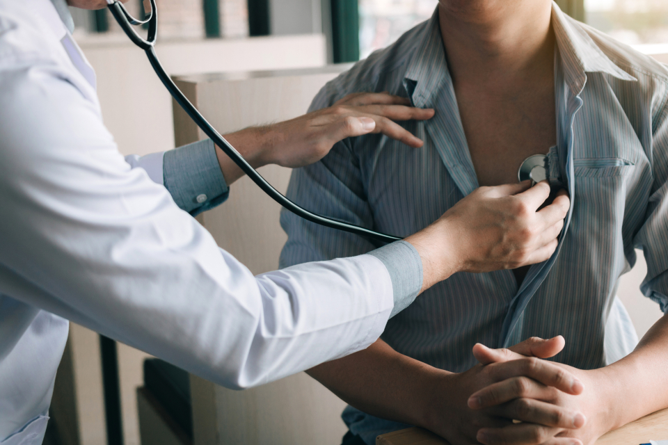 Läkare lyssnar på patients hjärta i ett stetoskop.